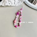 Detail of pink beaded phone strap featuring bear, star and heart charms on a white surface - Rose Red Bear