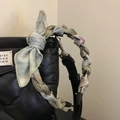 Close-up of black quilted leather handbag handle wrapped with colorful silk twilly scarf - Green