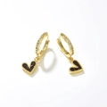 Detailed macro view of gold hoop earrings with heart charms and black cubic zirconia stones - Black