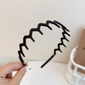 Matte black wavy headband with non-slip teeth for secure hair styling in a hand-held view - Large Teeth / Black