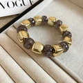 Détail d'un bracelet en perles acryliques avec des perles carrées dorées et rondes violettes - Gris