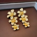 Macro detail of golden cascading flower earrings with vintage brushed metal texture - Gold Flower Tassel Style / Gold