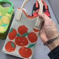 Beige knitted sunflower tote bag with orange fruit pattern held in hand - Orange Pattern Red Beige