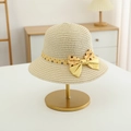 Detail of light beige straw sun hat with yellow polka dot bow on a display stand - Hat / Beige