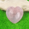Natural heart-shaped pink quartz worry stone resting on green grass for healing - Rose Quartz