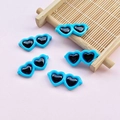 Close-up of five blue heart-shaped resin charms on a pink background with mini bamboo raft - 28*12mm / Dark Blue