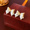 Détail de boucles d'oreilles nœud plaquées or 14K sur une boîte en cuir vintage - Or