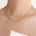 Minimalist silver chain necklace with oval links worn by a model on a soft beige background - Embossed Necklace / Steel