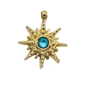 Macro shot of gold sunburst star pendant with a sparkling blue cubic zirconia center - Lake Blue Rhinestone