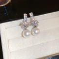 Detalle de pendientes de nudo plateados con circonitas y perlas blancas finas - Pendientes de Botón de Perla y Circonita Plateados Anudados (HE17615)