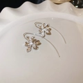 Macro shot of silver iris flower earrings with hammered texture in white ceramic dish - Silver