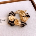 Detailaufnahme eines Leopardenmuster-Gliederarmbands auf einem beigen Leinenhintergrund - Armband / Gold Leopardenmuster