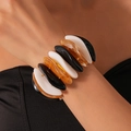 Nahaufnahme eines klobigen geometrischen Acryl-Stretch-Armbands mit Marmormuster - Mehrfarbiger gedrehter ovaler Stil