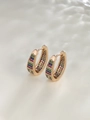 Detalle macro de pendientes de aro dorados con gemas multicolores sobre fondo texturizado - Circonita de Colores / Chapado en Oro de 18K - Multicolor