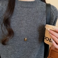 Gros plan d'un long collier à perles avec pendentif œil de tigre sur un pull gris - 29# Pendentif Pierre Précieuse Rectangulaire Chaîne Perlée Argent