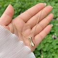 Hand holding a 18K gold plated balloon style alphabet A-Z pendant with a smooth surface - Gold I