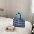 Close-up of blue gingham canvas lunch bag with woven handles on a white bedding background - Blue Gingham