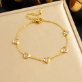 Bracciale a cuore in acciaio placcato oro con gemme viola su fondo beige - Bracciale cuore viola (B1842)