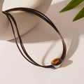 Dettaglio della collana con ciondolo ovale in occhio di tigre e cordino intrecciato marrone - Collana multistrato marrone