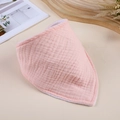 Flat lay of pink muslin baby bib with gauze texture on a minimalist beige desk - Pink