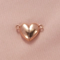 Primer plano de cierres magnéticos de corazón en oro rosa para pulseras en tela rosa - Oro rosa