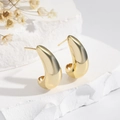 Minimalist golden crescent drop earrings on white stone base with soft shadows - EH771 Gold Crescent Studs