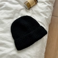 Dettaglio del berretto in maglia di lana nera con trama morbida su lino bianco - M (56-58cm) / Nero