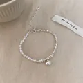 Détail du bracelet vintage en perles et pendentif cœur argenté sur tissu en lin - Bracelet