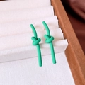 Detail view of matte green knotted earrings with spray paint texture on a jewelry tray - Knot Style / Green