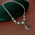 Detailed view of silver leaf necklace with green teardrop gem on green velvet box - Necklace - Silver - Green