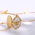 Golden oval locket necklace featuring white mother of pearl and a gold butterfly detail - Butterfly Shell Locket / Gold