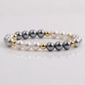 Elegante pulsera de perlas blancas y grises con espaciadores dorados sobre fondo reflectante - Pulsera Mezcla Blanco Gris Oro