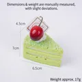 Green triangle mousse cake squishy toy with white icing and red cherry decoration - Green