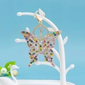 Dettaglio macro del portachiavi a fiocco dorato con cristalli colorati su supporto bianco - Farfalla 31