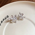 Detail of silver-tone metal flower earrings with hammered texture on ceramic plate - Silver