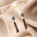 Detailed close-up of fan-shaped earrings with pearls and brown geometric pendants on a stand - Ear Hook S3092