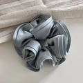 Macro detail of ruffled grey-blue satin hair scrunchie with premium silk texture - Blue
