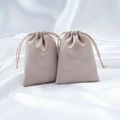 Beige satin jewelry pouches with drawstring closure on white silk background - Champagne