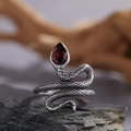 Close-up of snake ring with garnet gemstone on rough stone and wooden background - Natural Garnet Snake Ring LR286