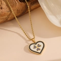 Detalle de collar de corazón dorado con trébol de gemas azules sobre seda blanca y madera - Collar de diamantes de imitación azules con concha de corazón blanco (K409)