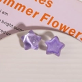 Close-up of purple resin star charms with marble texture and glitter for DIY crafts - Purple