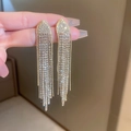 Detailansicht eleganter goldener Quasten-Ohrringe mit glitzernden Kristallen und Blättern - Dreieck Pfeil Quasten Ohrringe / Gold