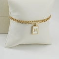 Detalle de la pulsera dorada de doble cadena con un colgante de letra N en concha blanca - Letra N