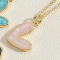 Macro detail of a heart pendant with pink shell inlay and golden grid texture finish - Pink