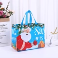 Blue Christmas non-woven gift bag featuring Santa Claus and Santa is here text - Christmas Blue