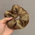 Detailed close-up of golden brown satin scrunchie with elegant ruffled texture - Brown