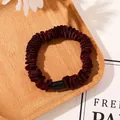 Detail view of burgundy pleated satin hair scrunchie with a sleek black plastic buckle - Tencel Velvet Wine Red