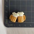 Detailed view of yellow resin cartoon beer mug charms with smiley faces on a cutting mat - Two Beer Mugs