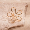 Detailopname van een gouden bloemring met parel op een natuurlijke stenen achtergrond - Gouden Bloem Stijl (Parel Decor)