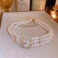Detailed macro view of triple-strand pearl necklace with vintage crystal sunburst pendant - Gold Multi-layer Pearl Necklace